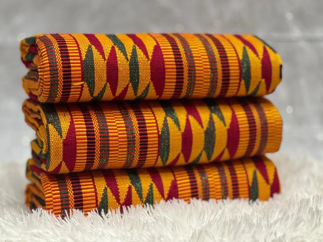 Folded Ghanaian Kente cloth, bands of gold, maroon, and green with black geometric motifs.